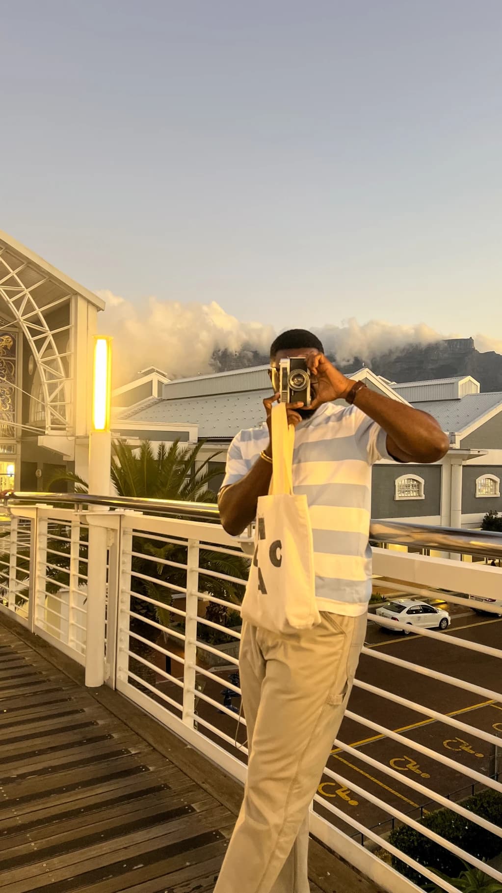 A person taking a photograph on a balcony at sunset