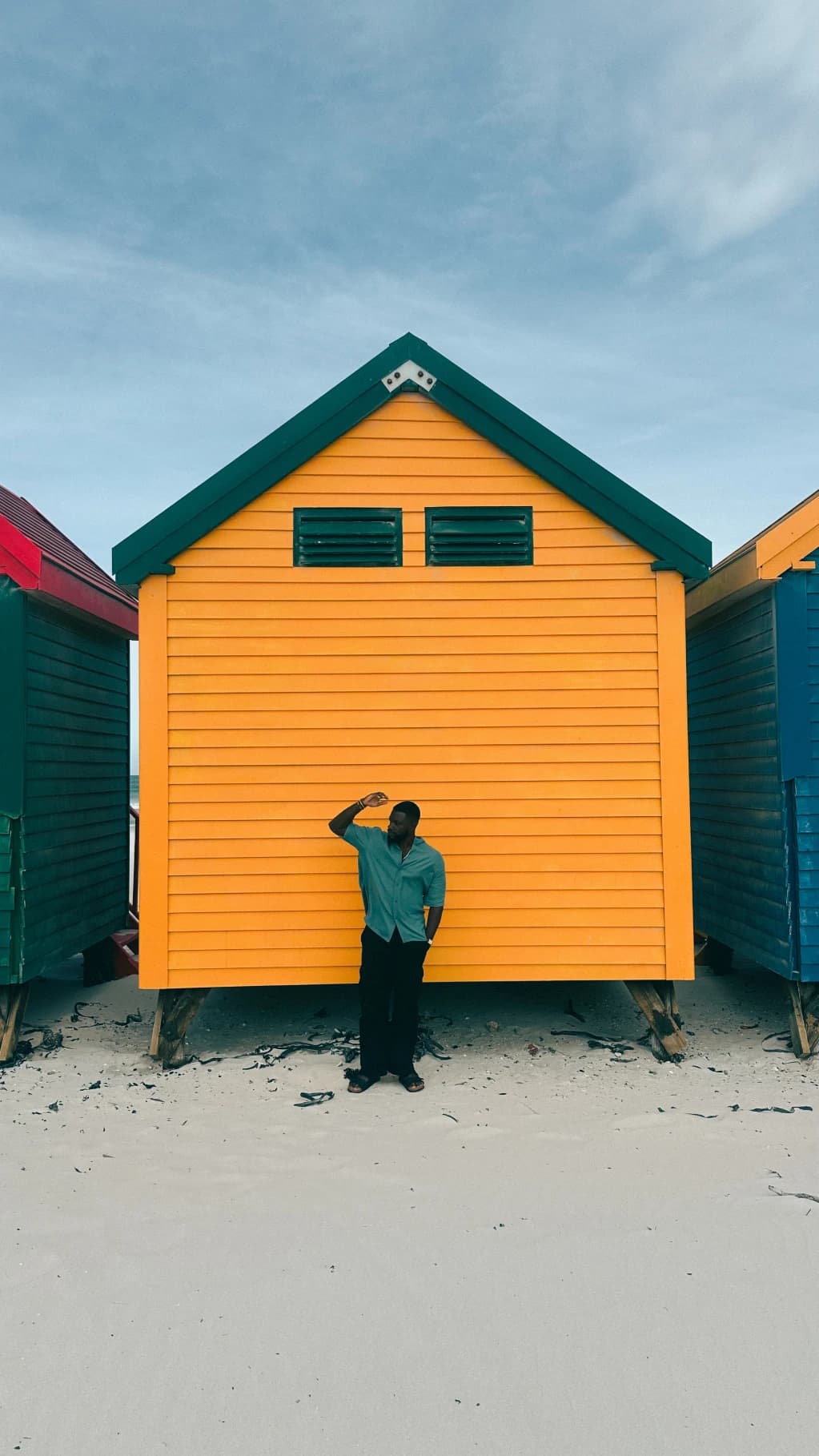 A person standing outside a bright yellow beach hut
