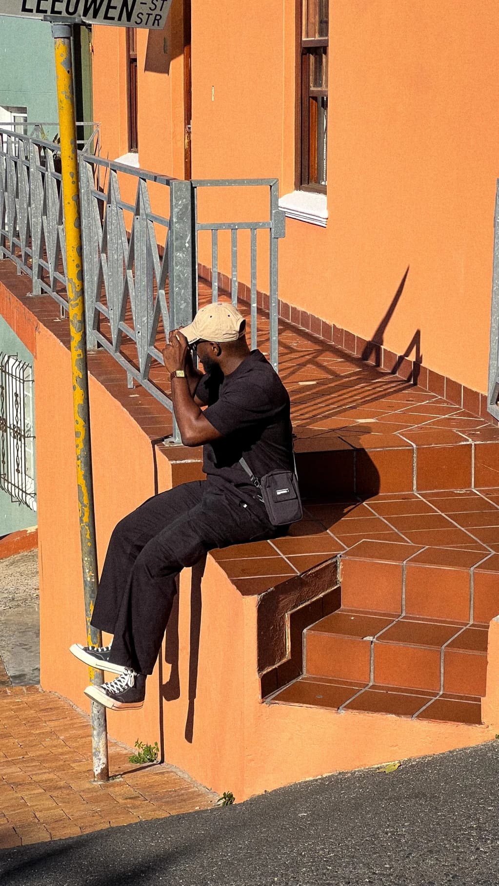 A person sitting on steps beside an orange building