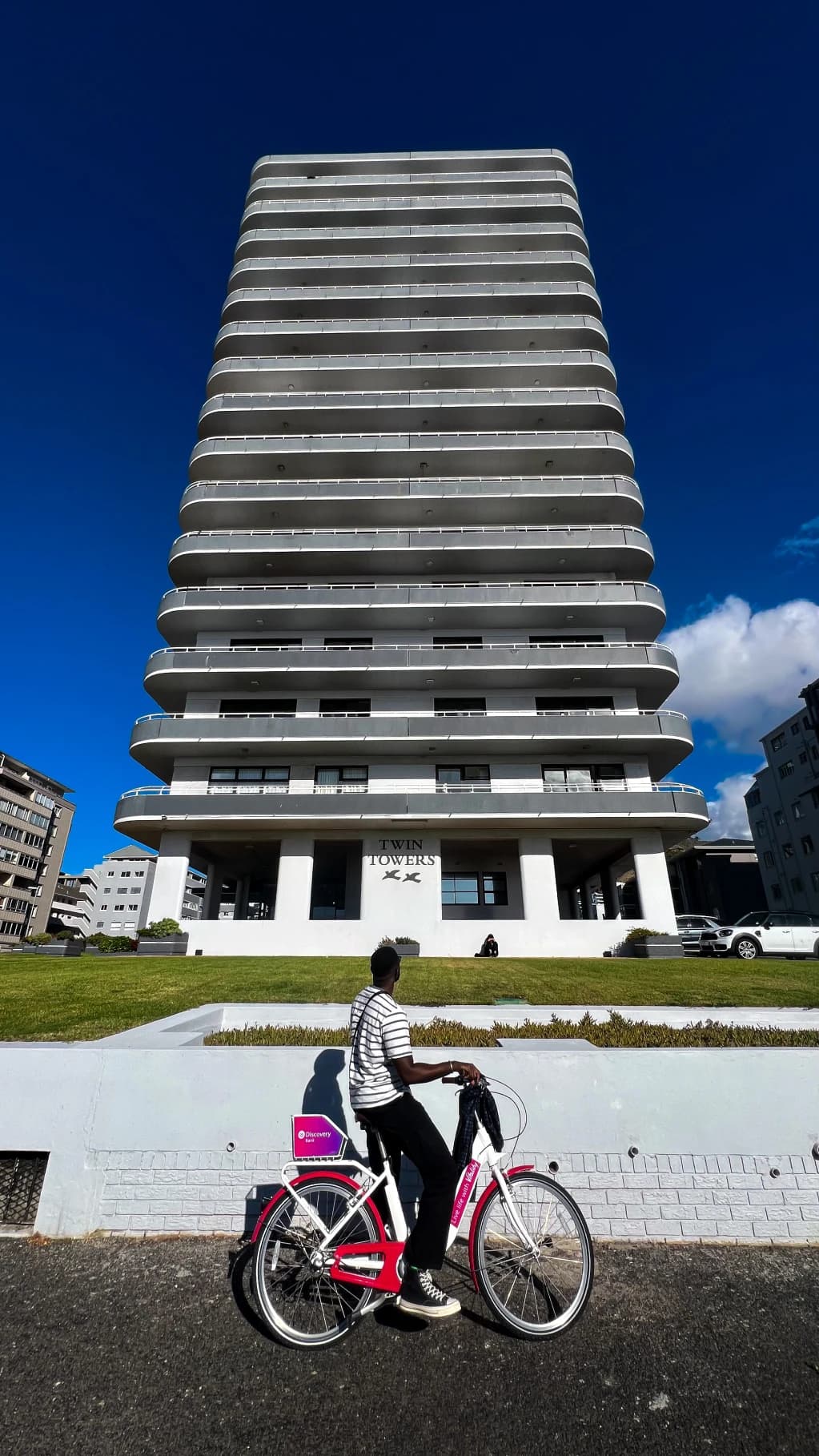 A tall apartment building above a passing cyclist
